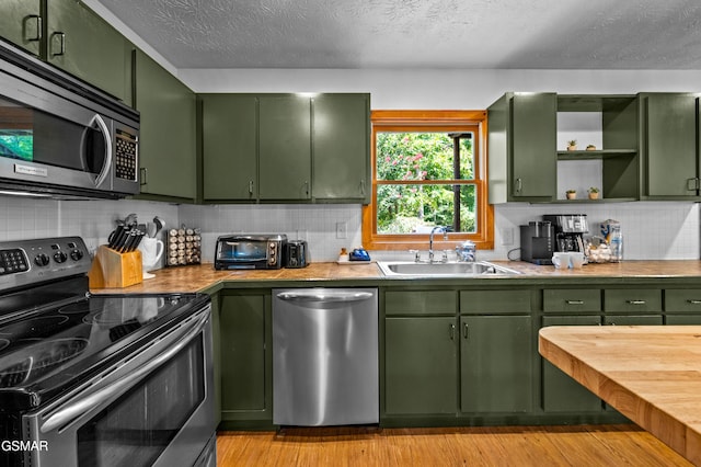 kitchen with appliances with stainless steel finishes, green cabinets, and sink