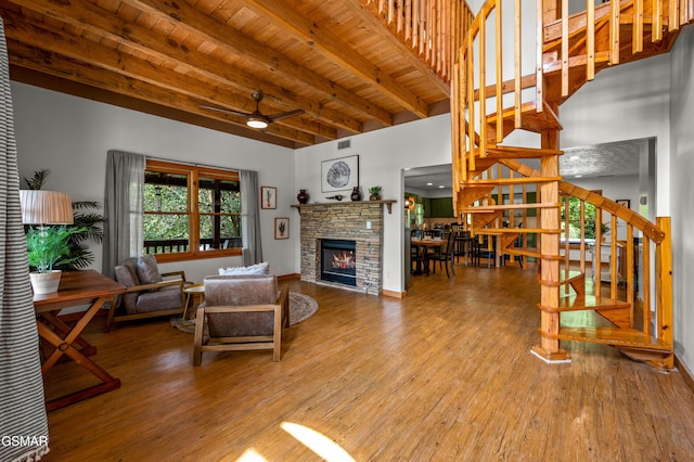 living room with beam ceiling, ceiling fan, hardwood / wood-style floors, a fireplace, and wood ceiling