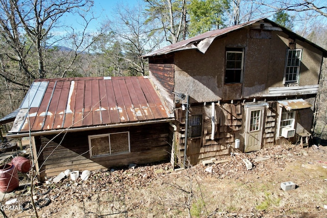 rear view of property with cooling unit, a standing seam roof, and metal roof