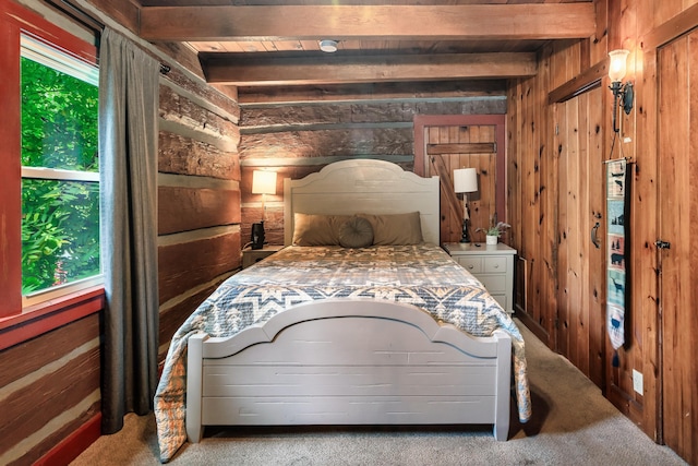 carpeted bedroom with beam ceiling and wood walls