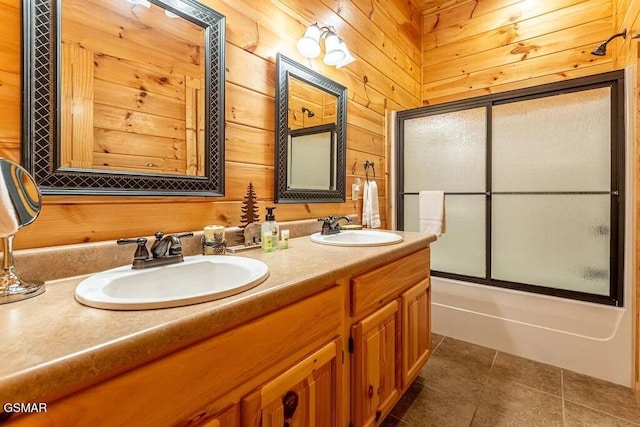 bathroom featuring tile patterned flooring, vanity, wood walls, and bath / shower combo with glass door