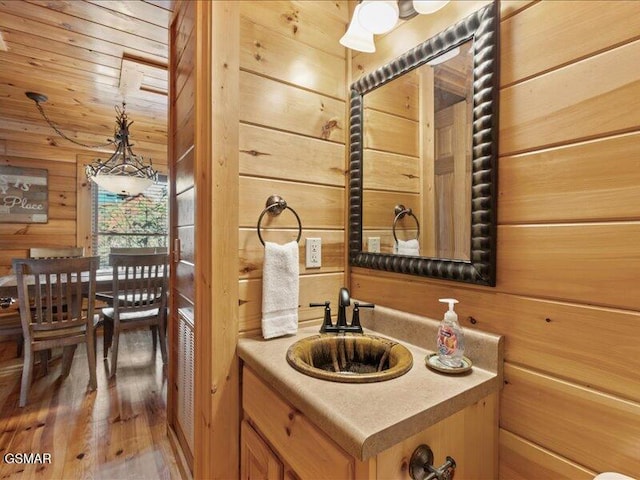 bathroom featuring hardwood / wood-style floors, vanity, and wood walls