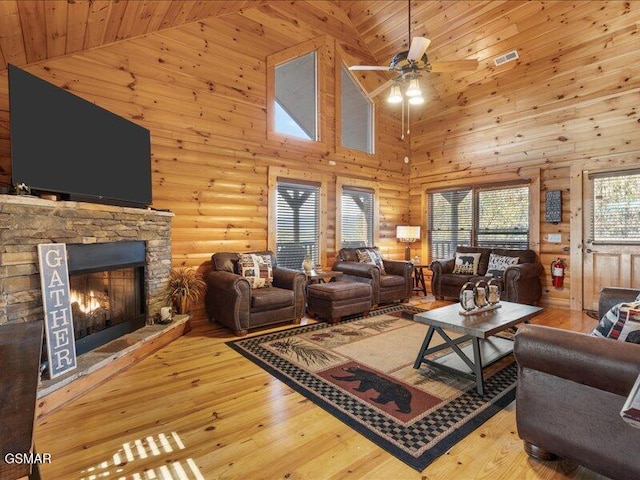 living room featuring rustic walls, ceiling fan, wooden ceiling, high vaulted ceiling, and a fireplace