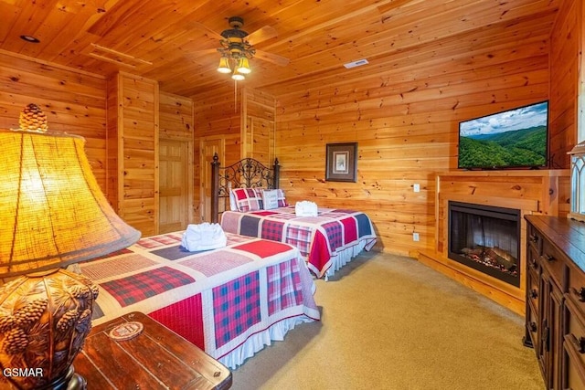 carpeted bedroom featuring ceiling fan, wooden ceiling, and wood walls