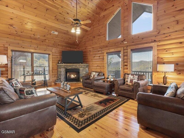 living room featuring log walls, high vaulted ceiling, ceiling fan, and a stone fireplace