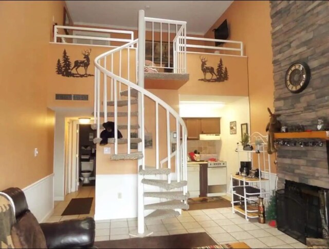 staircase featuring tile patterned flooring, a high ceiling, and a fireplace