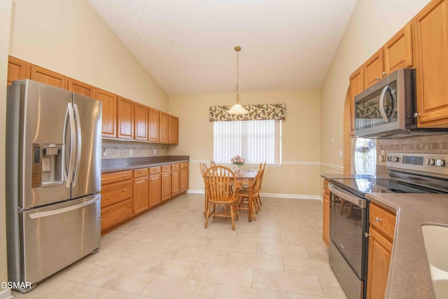 kitchen with baseboards, hanging light fixtures, vaulted ceiling, stainless steel appliances, and backsplash