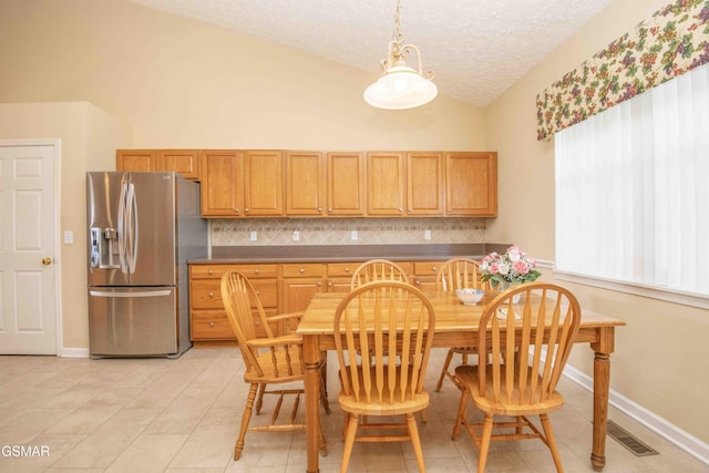 dining area featuring light tile patterned floors, a textured ceiling, visible vents, baseboards, and vaulted ceiling