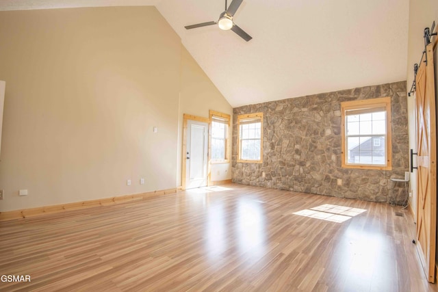 unfurnished room featuring light wood-style floors, ceiling fan, high vaulted ceiling, and baseboards