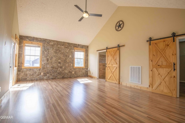 interior space featuring wood finished floors, visible vents, ceiling fan, and a barn door