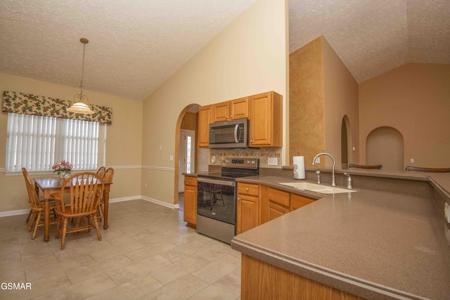 kitchen with arched walkways, stainless steel appliances, a sink, hanging light fixtures, and tasteful backsplash