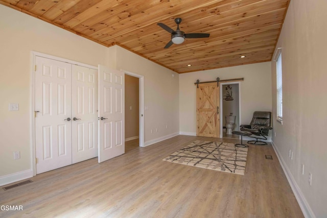 unfurnished bedroom featuring visible vents, a barn door, wood ceiling, wood finished floors, and baseboards