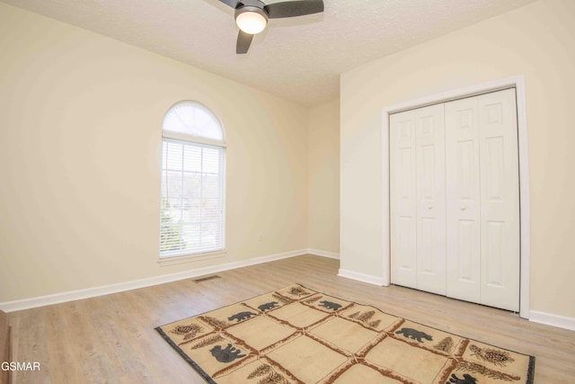 unfurnished bedroom featuring light wood-style flooring, a closet, visible vents, and a textured ceiling