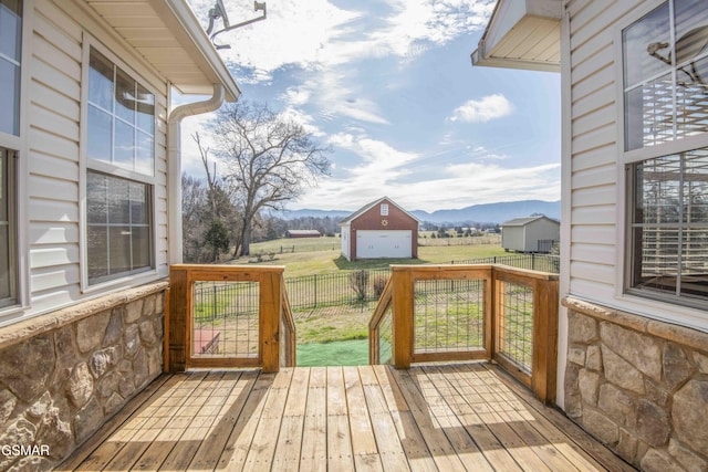 wooden terrace with a yard, a rural view, fence, and a mountain view