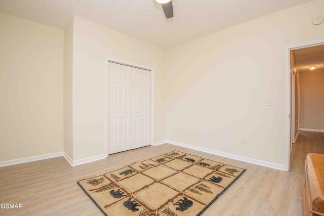 interior space with light wood-style floors, baseboards, and a textured ceiling