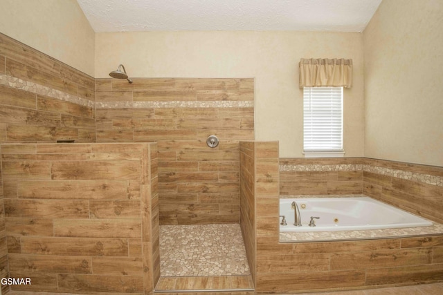 full bathroom with a textured ceiling, a tub with jets, and tiled shower