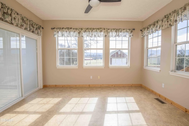 unfurnished room with baseboards, visible vents, and ceiling fan