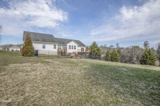 back of property featuring fence, a lawn, and a wooden deck