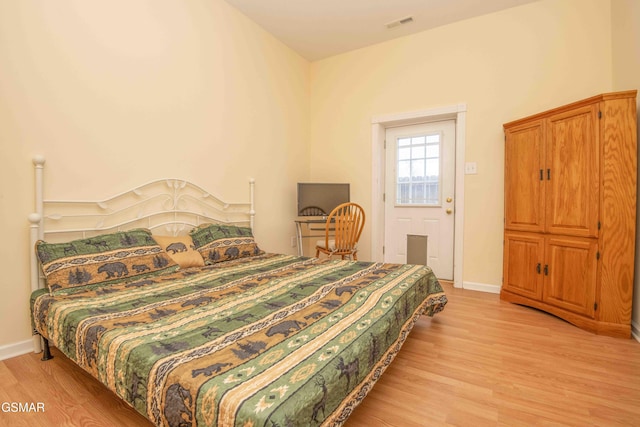 bedroom with light wood finished floors, visible vents, and baseboards