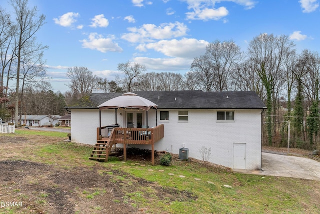 rear view of property featuring a gazebo, cooling unit, a deck, and a yard