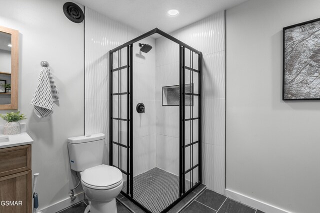 bathroom featuring tile patterned flooring, vanity, toilet, and tiled shower