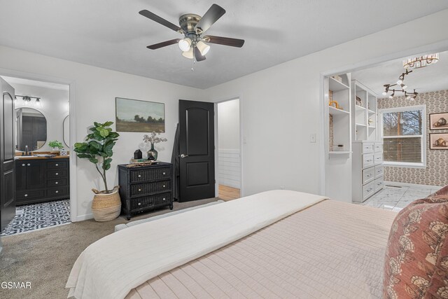 carpeted bedroom with ensuite bathroom and ceiling fan