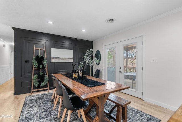 dining area with french doors, crown molding, and light hardwood / wood-style flooring