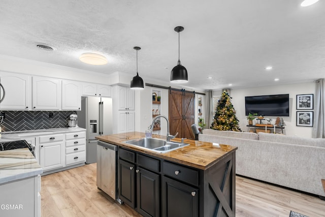 kitchen with white cabinets, a barn door, sink, and appliances with stainless steel finishes