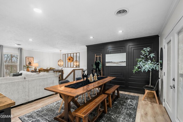 dining room with light hardwood / wood-style floors and crown molding