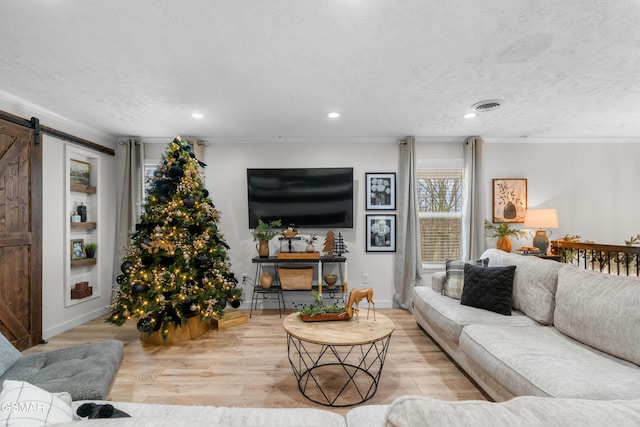 living room with a barn door, light hardwood / wood-style floors, and a textured ceiling