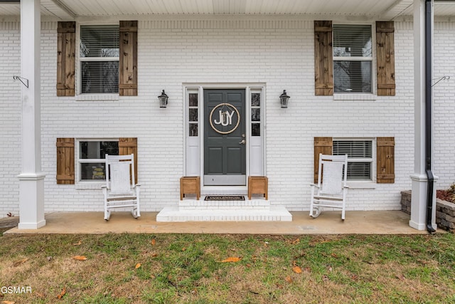 view of exterior entry featuring a porch and a yard