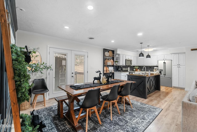 dining room featuring french doors, light hardwood / wood-style flooring, crown molding, and sink