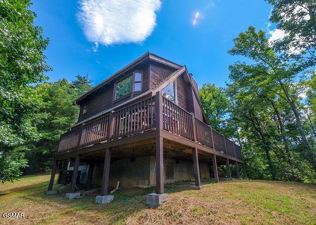 back of house featuring a lawn and a wooden deck