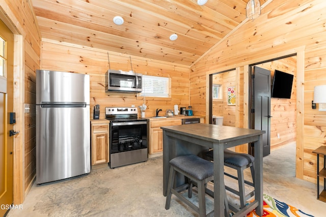 5145 E Parkway Pkwy, Cosby, TN 37722 - kitchen with stainless steel appliances, lofted ceiling, concrete flooring, wood walls, and light brown cabinetry