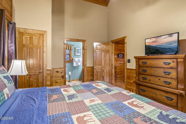 bedroom featuring wood walls and a high ceiling