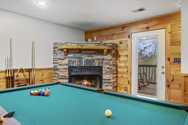 recreation room with wooden walls, a fireplace, a textured ceiling, and billiards