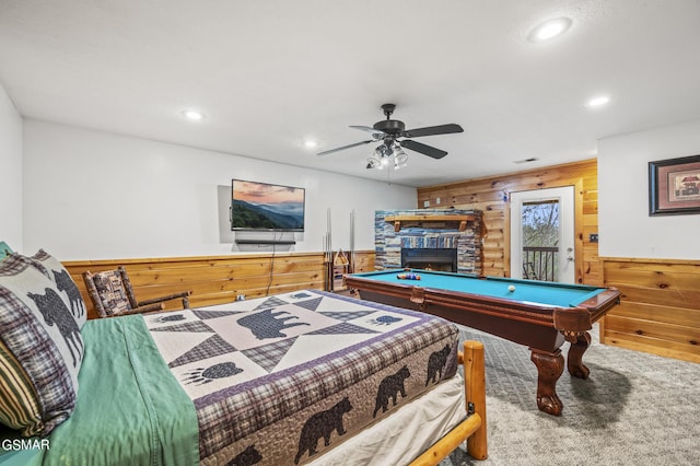 playroom with carpet flooring, ceiling fan, a stone fireplace, wooden walls, and pool table