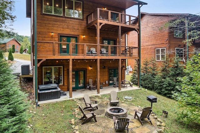 rear view of property with french doors, a fire pit, central air condition unit, a balcony, and a patio