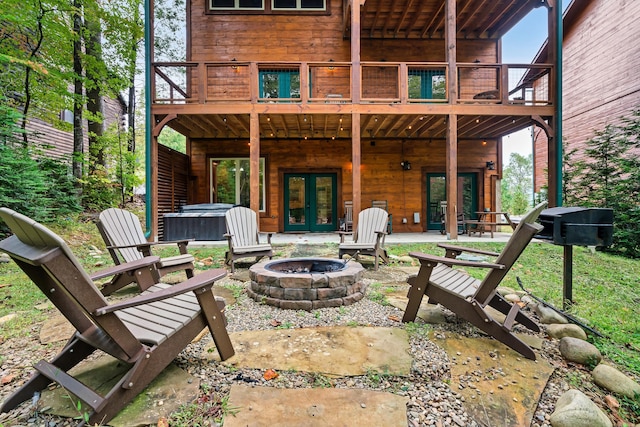 view of patio / terrace with french doors, a hot tub, a deck, and an outdoor fire pit