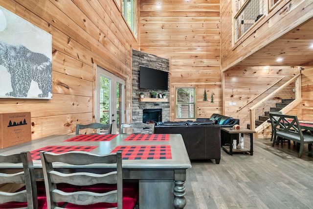 dining space with wood-type flooring, a towering ceiling, wooden walls, and french doors