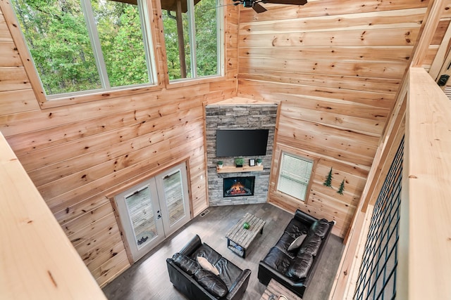 living room featuring hardwood / wood-style flooring, ceiling fan, wood walls, and a fireplace