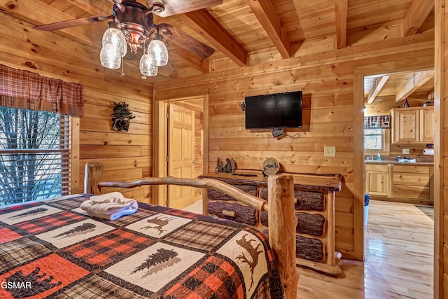 bedroom with beam ceiling, wood ceiling, wooden walls, and light hardwood / wood-style flooring