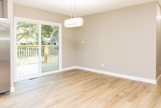 unfurnished dining area with light wood-type flooring and a chandelier