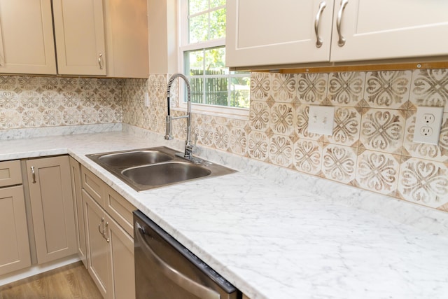 kitchen with decorative backsplash, stainless steel dishwasher, light stone countertops, and sink