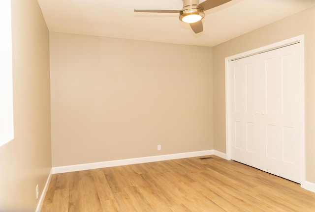 unfurnished bedroom with ceiling fan, light hardwood / wood-style flooring, and a closet