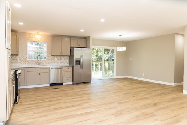 kitchen with pendant lighting, sink, light wood-type flooring, and stainless steel appliances