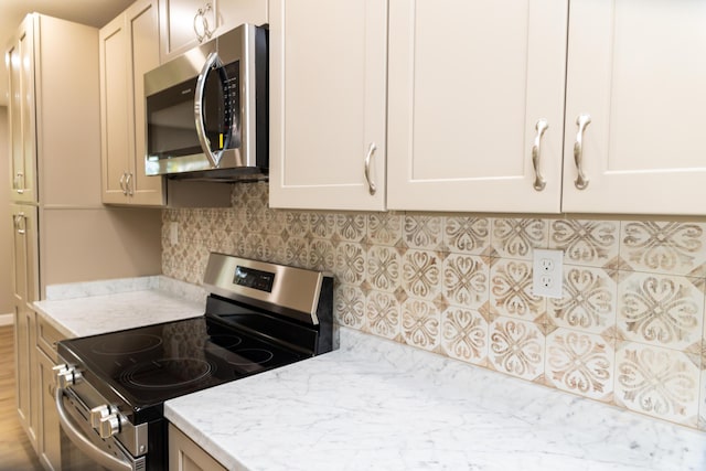 kitchen with light stone counters, appliances with stainless steel finishes, and tasteful backsplash