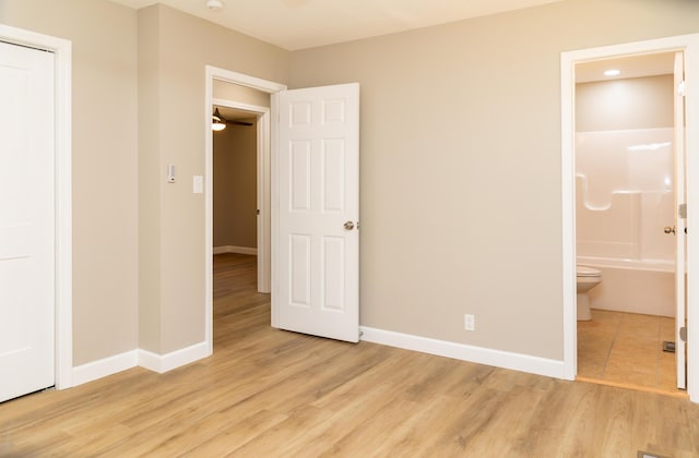 unfurnished bedroom with ensuite bath and light wood-type flooring