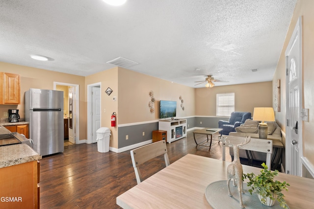 dining space with ceiling fan, dark wood-type flooring, and a textured ceiling