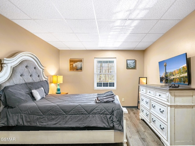 bedroom with a drop ceiling and light hardwood / wood-style flooring